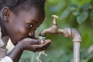 african child drinking water from faucet