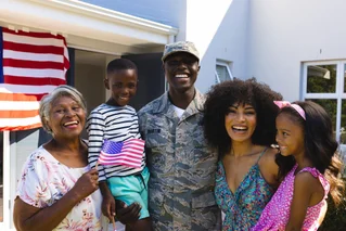 Happy family of a military member, in front of their house with an American flag