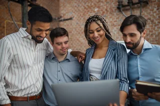 Cheerful group of young adults reading on laptop