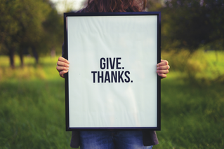 person holding "Give. Thanks." sign