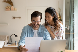 man and woman looking at document happily