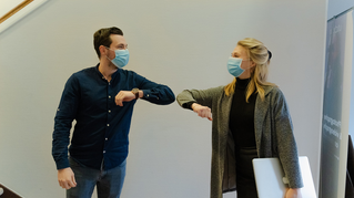 two people in masks bumping elbows for social distance 