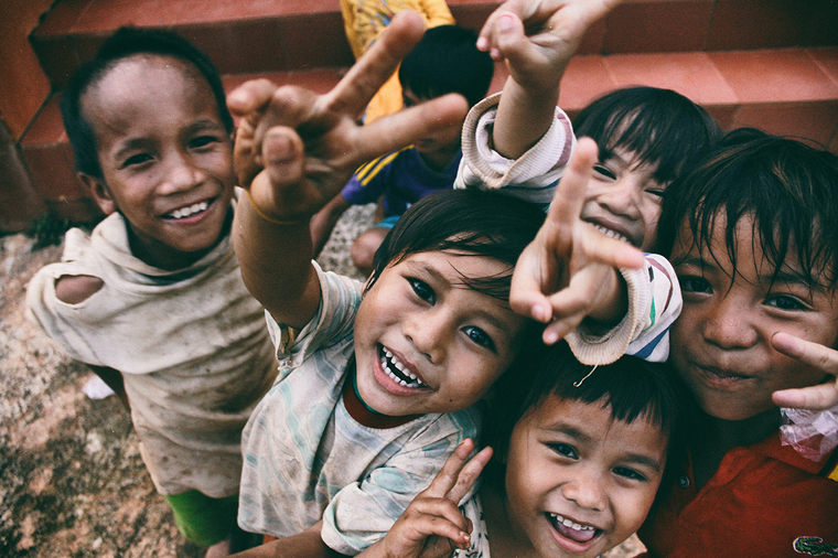 A group of children in an underdeveloped country smiling and giving peace signs