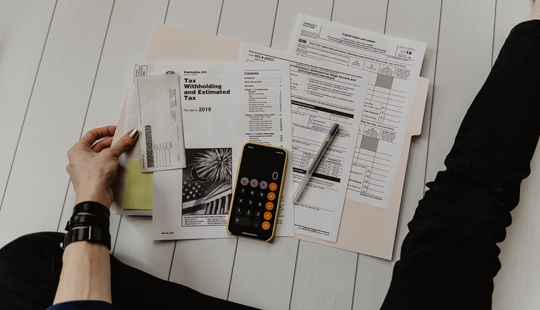 Someone sits at a desk with their tax documents laid out on the table before them.