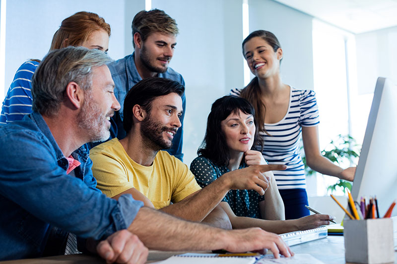 A group of team members work together around a computer