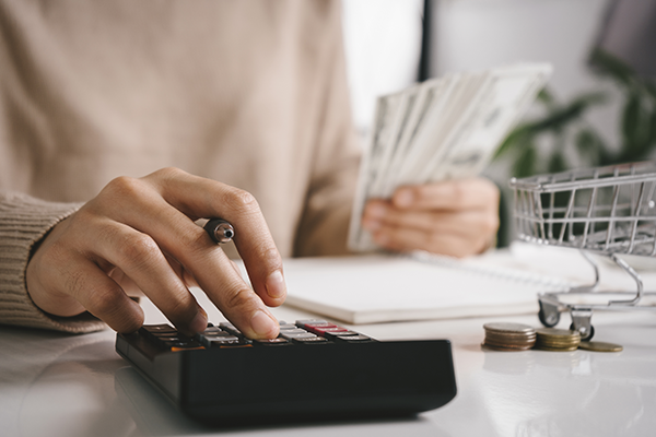 An individual sits at a desk calculating bills