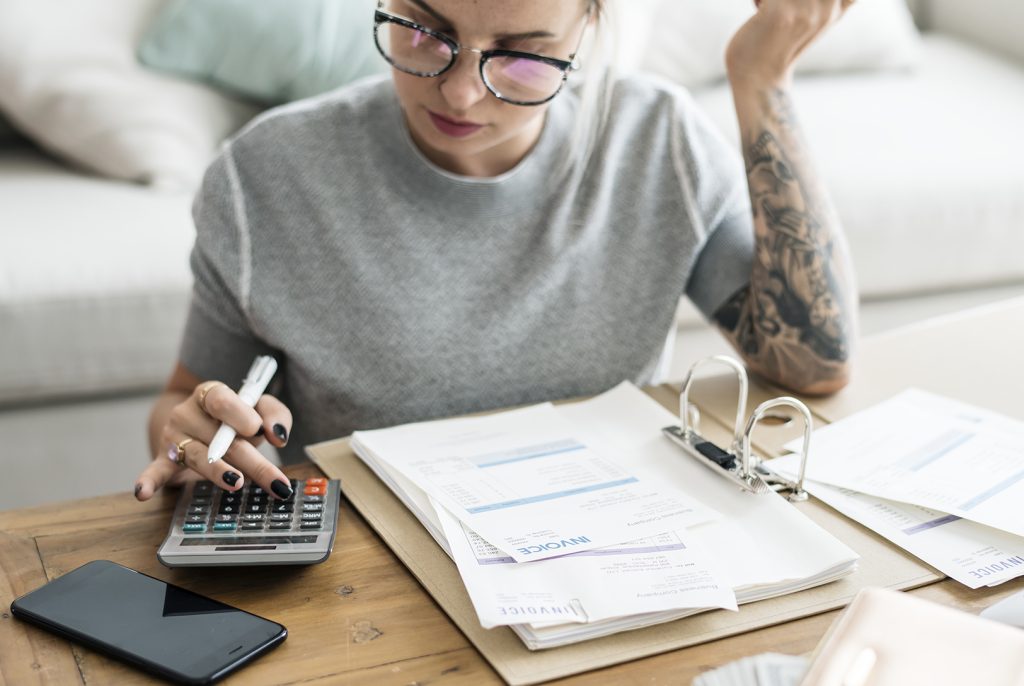 A young woman with a calculator, looking over her taxes