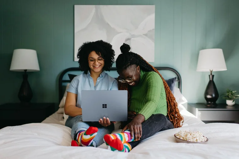 Two happy people sitting in a bed and searching on a laptop