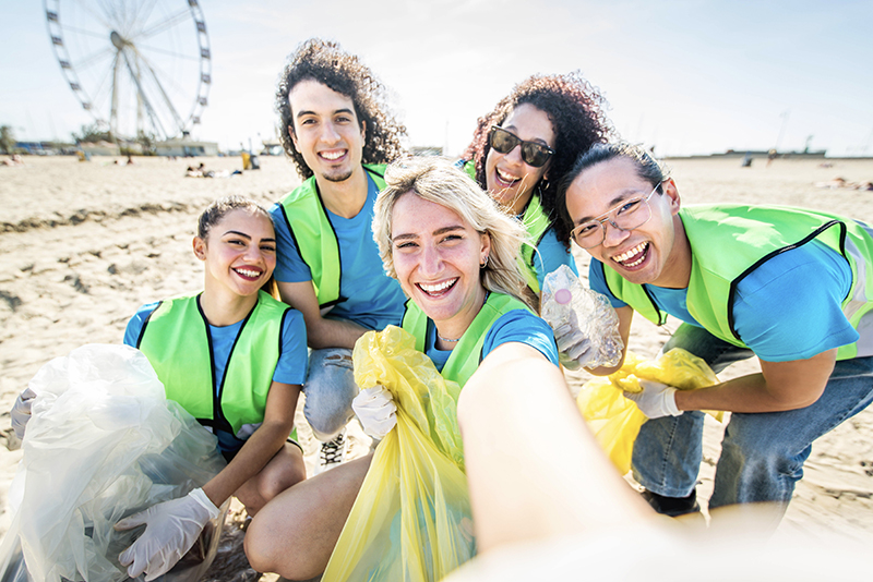 Group of eco volunteers picking up plastic trash on the beach