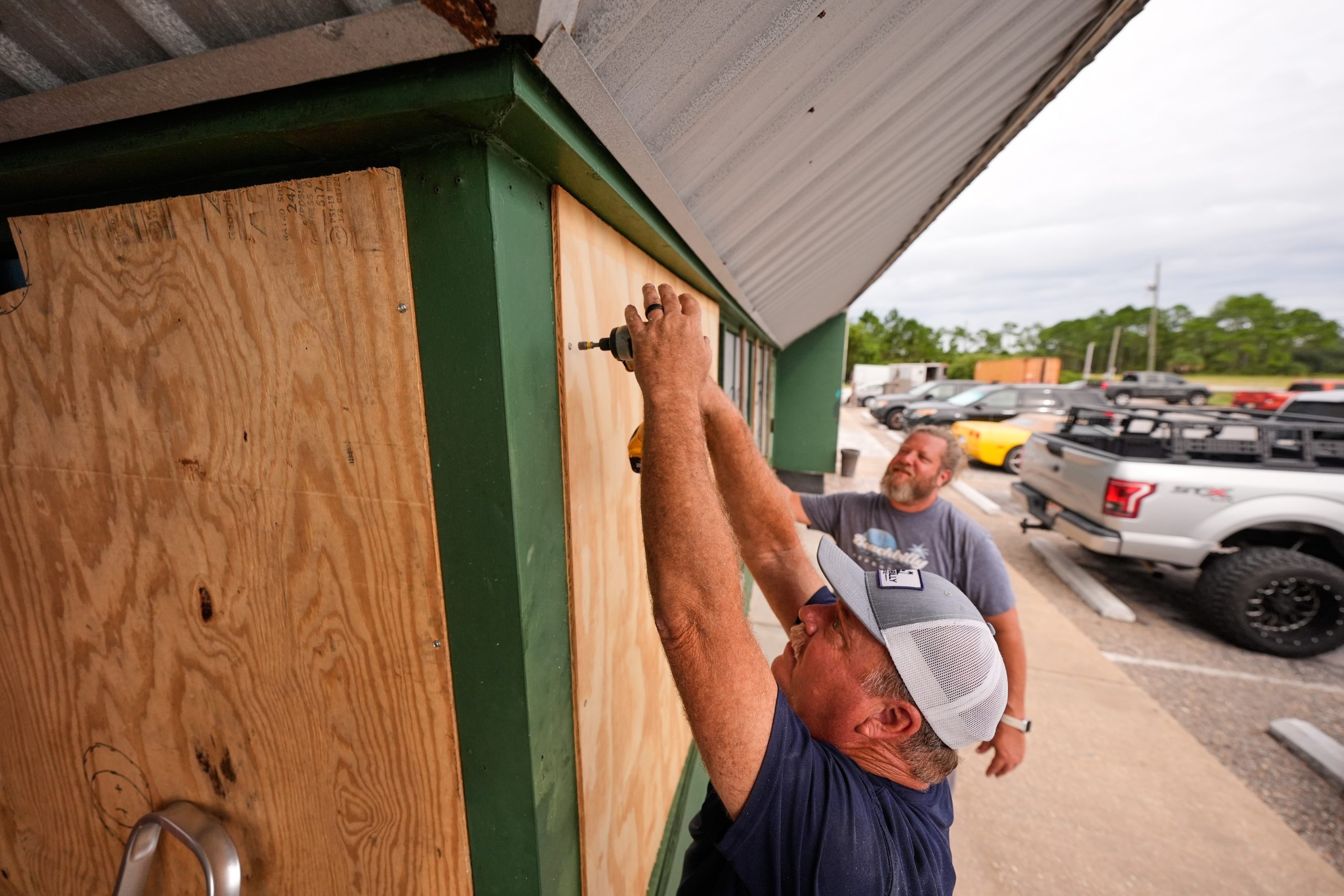 Image of business owners boarding up their windows in preparation for the hurricane