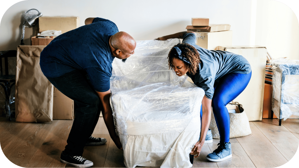 Two people lifting wrapped furniture